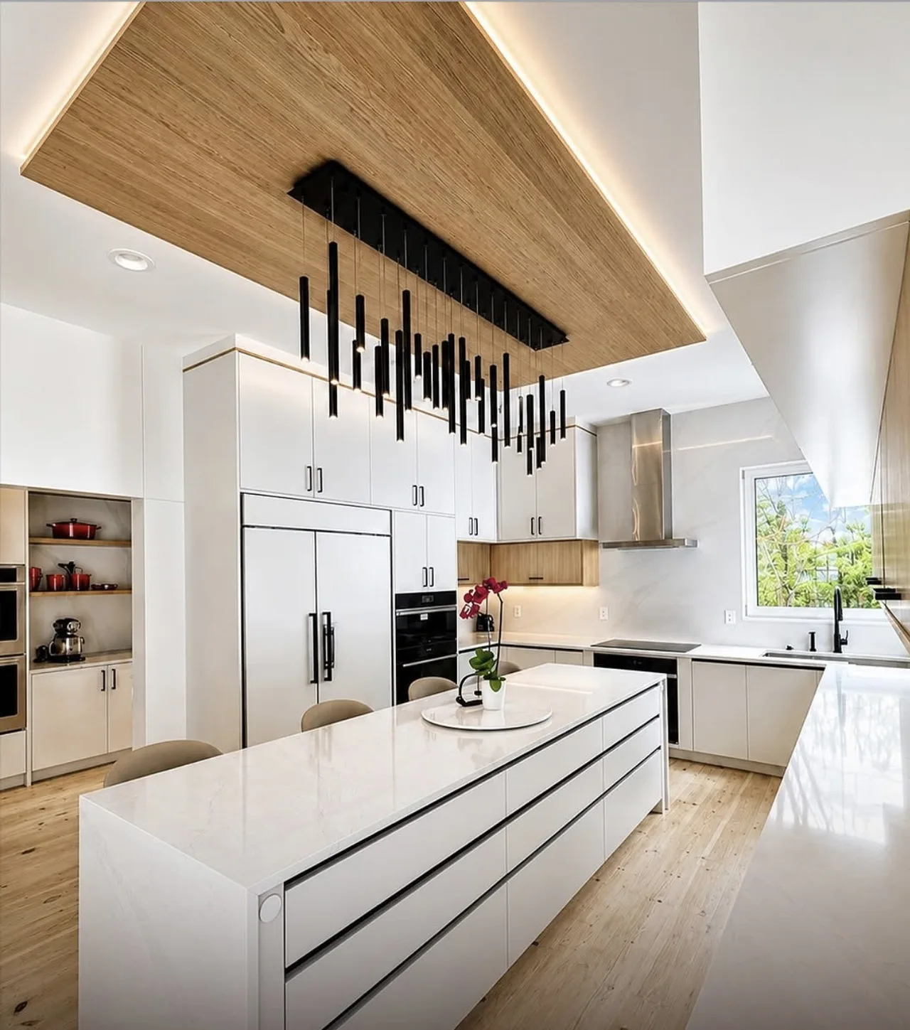 Kitchen at the Bedford Residence with a full-length stone-topped island, white slab cabinetry and a backlit white oak ceiling panel